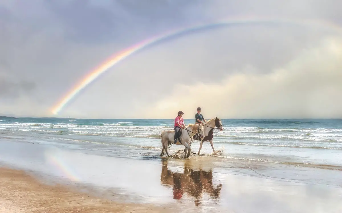 A photo of a person riding a horse on the beach in France